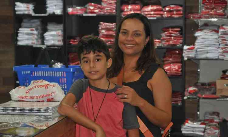 Silvia e o filho Arthur, que usa uma camisa vermelha. No fundo vrios uniformes  venda