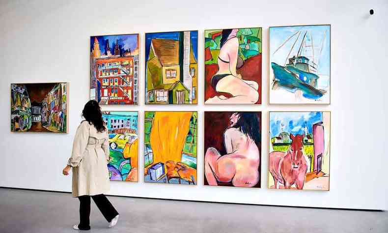 Mulher circula pela galeria de arte, observando novas telas de Bob Dylan penduradas na parede 