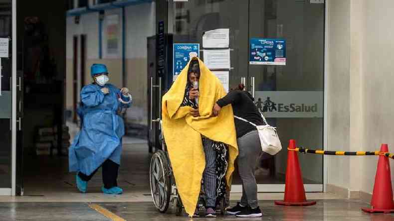 Paciente com covid em cadeira de rodas  recebido por um mdico na entrada de pronto-socorro no Peru