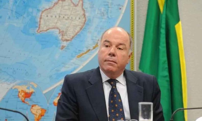 Chanceler brasileiro já realizou 55 encontros bilaterais com chanceleres de 54 países(foto: Wilson Dias/Agência Brasil) Mauro Vieira sentado a mesa com mapa mundi e bandeira do Brasil ao fundo