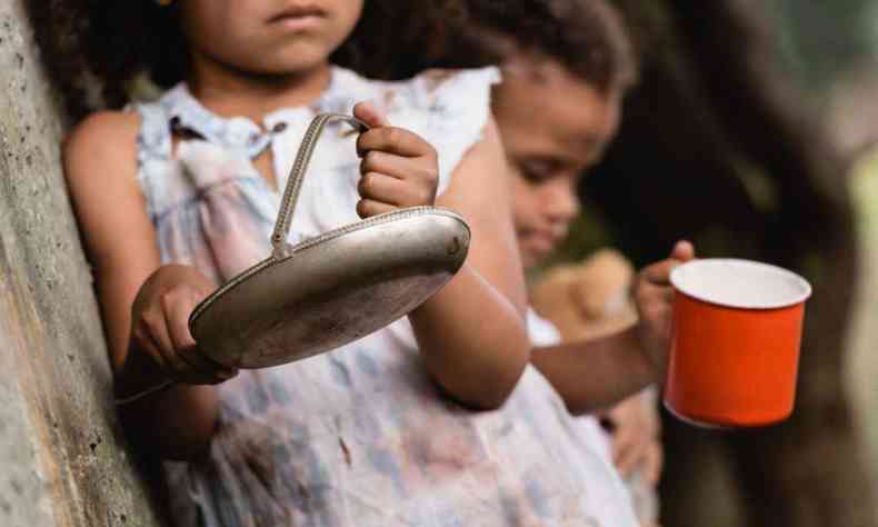 Duas crianças seguram prato sem comida, imagem indica fome 