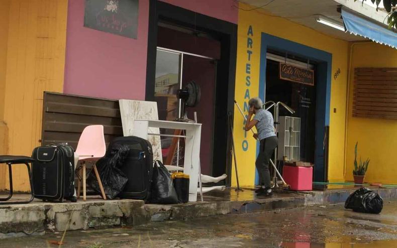 Comerciantes retiraram a lama das lojas que ficam próximos ao Córrego Cachoeirinha, na Avenida Bernardo Vasconcelos(foto: Edésio Costa/EM/DA PRESS) Mulher retirando a lama da calçada
