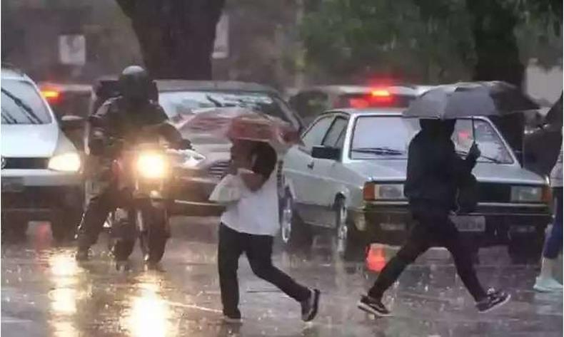 Avenida com carros e pessoas andando na chuva