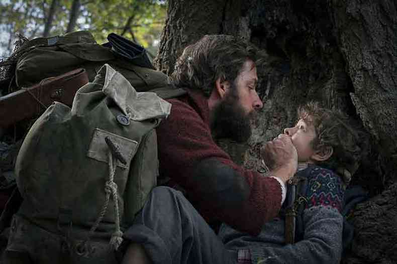 Numa floresta, homem tapa a boca de criança no filme Um lugar silencioso