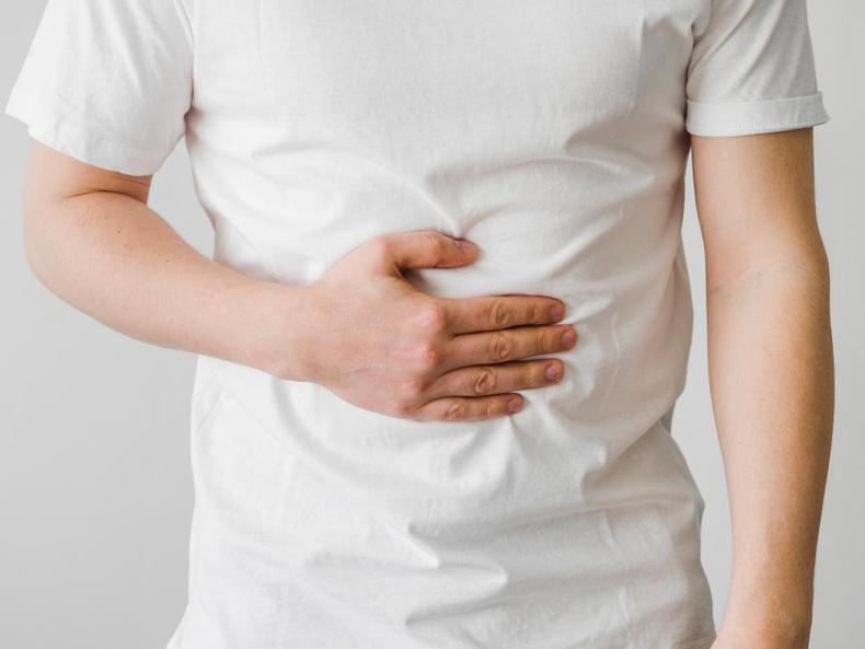Homem com blusa branca com a mo na barriga, em cima do estmago