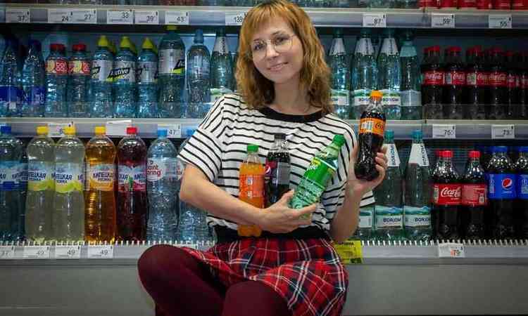 menina ruiva, de culos, no supermercado segurando vrias garrafas de refrigerante