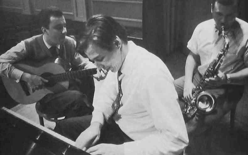 Joo Gilberto,  esquerda, toca violo. Ao centro, de terno, Tom Jobim toca piano. Atrs de Tom. Stan Getz toca saxofone