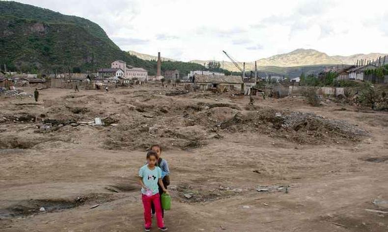 Foto de 18 de setembro mostra duas crian�as perto dos escombros de casas danificadas devido a enchentes do rio Tumen no final de agosto no distrito Sambong de Musan, na Coreia do Norte(foto: ANIL POKHREL/AFP)