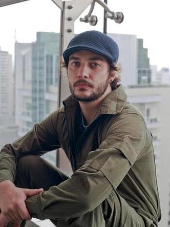 Cantor e compositor Vito Velasso olha para a cmera, ao fundo veem-se predios