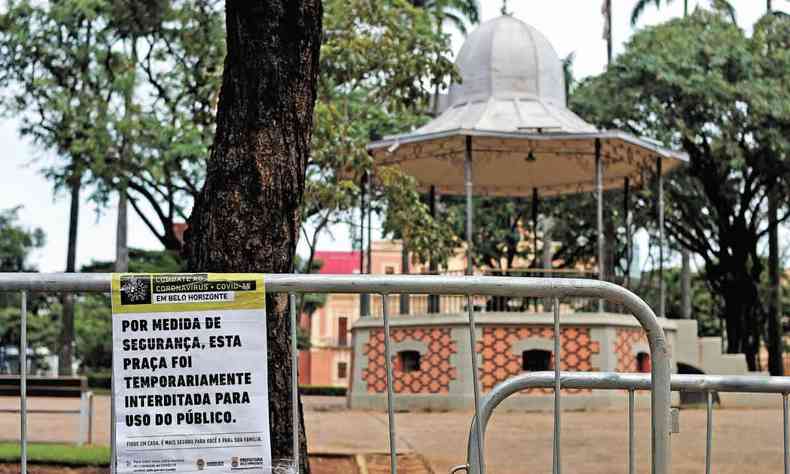 Cartaz avisa que a Praça da Liberdade, em BH, está interditada devido à pandemia. Ao fundo, vê-se o coreto