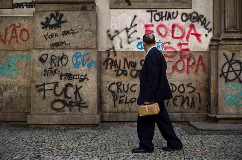 Transeunte observa pichaes feitas por manifestantes no Rio de Janeiro, em 18 de junho de 2013