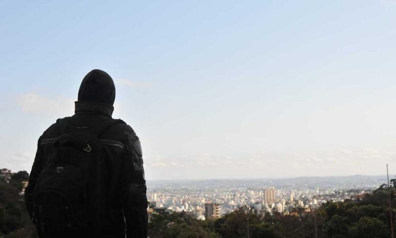 Homem agasalhado, de costas, observa a vista de Belo Horizonte 