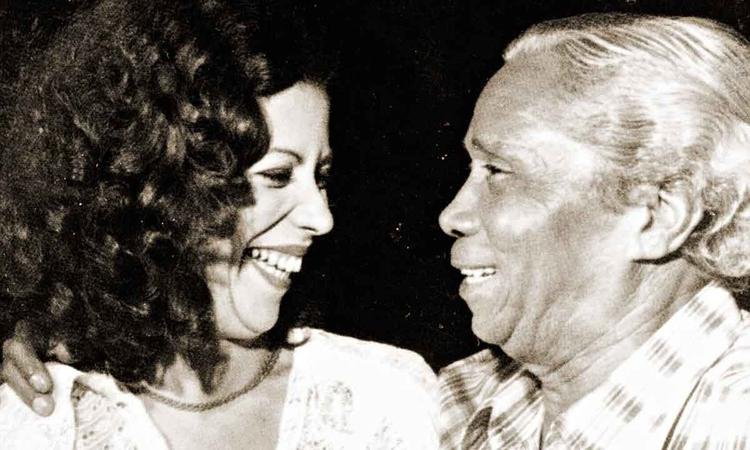 Beth Carvalho e Nelson Cavaquinho se abra�am e sorriem um para o outro
