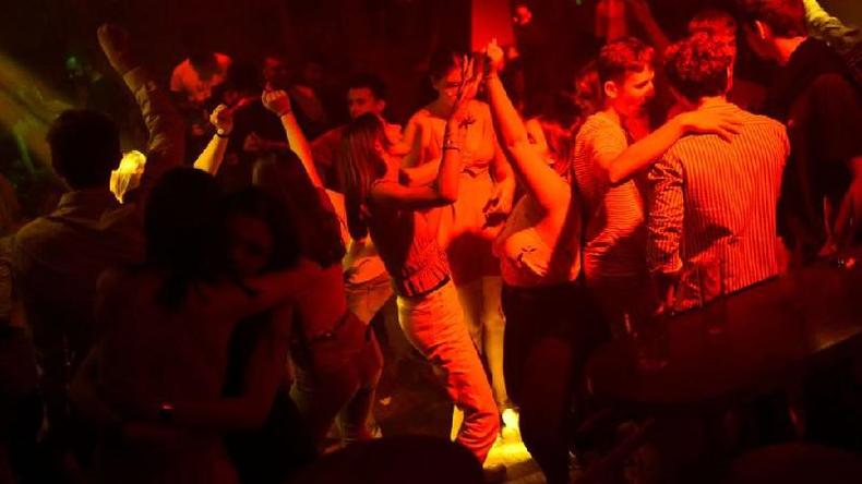 Jovens danam em um clube noturno sob luzes vermelhas