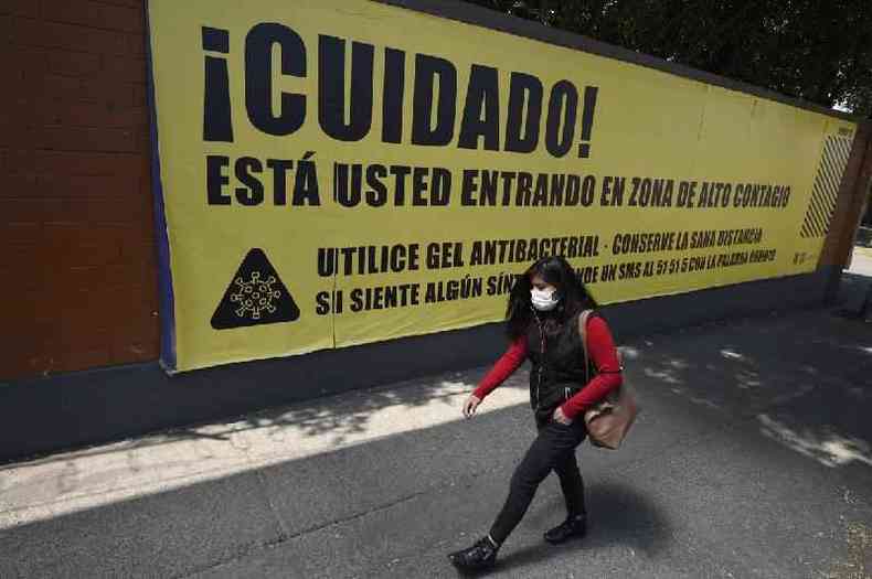 Uma mulher passa por um cartaz de aviso de uma rea de alto risco de contgio de covid-19 na Cidade do Mxico em 27 de abril de 2020 (Alfredo Estrella / AFP)