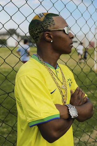 Jovem negro com o cabelo pintado com as cores da bandeira usa camisa da seleo brasileira
