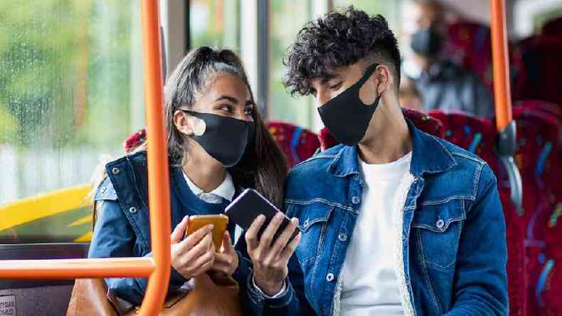 Um homem e uma mulher no ônibus usando máscaras