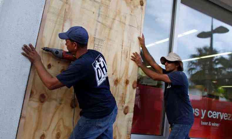 Moradores de Porto Rico protegem janelas contra o furaco com tapumes de madeira (foto: Ricardo ARDUENGO / AFP)