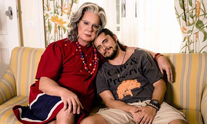 Luiz Fernando Guimares, vestido de mulher, abraa Bruno Gissoni. Os dois esto sentados no sof
