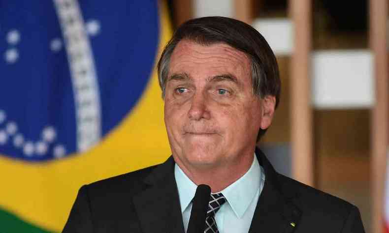 Bolsonaro srio em frente  bandeira do Brasil