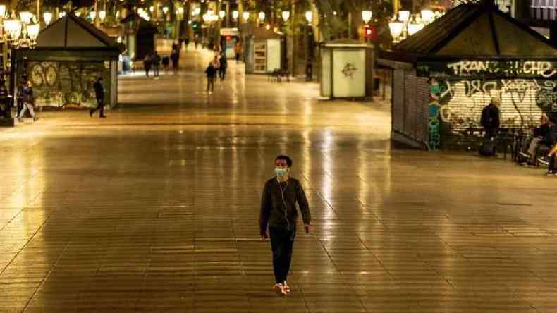Homem caminha na avenida Las Ramblas, Barcelona, aps toque de recolher imposto na Espanha como tentativa de conter segunda onda(foto: EPA/ENRIC FONTCUBERTA)