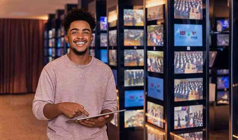 Jovem negro em uma biblioteca com um tablet na mo