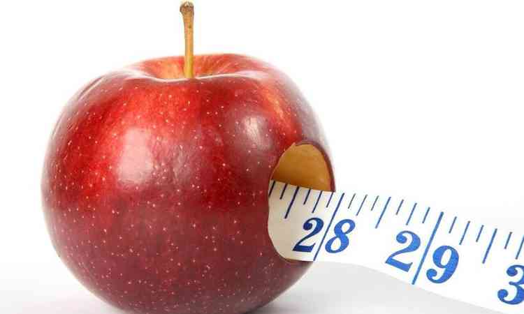 maçã com uma fita métrica saindo de um buraco da fruta
