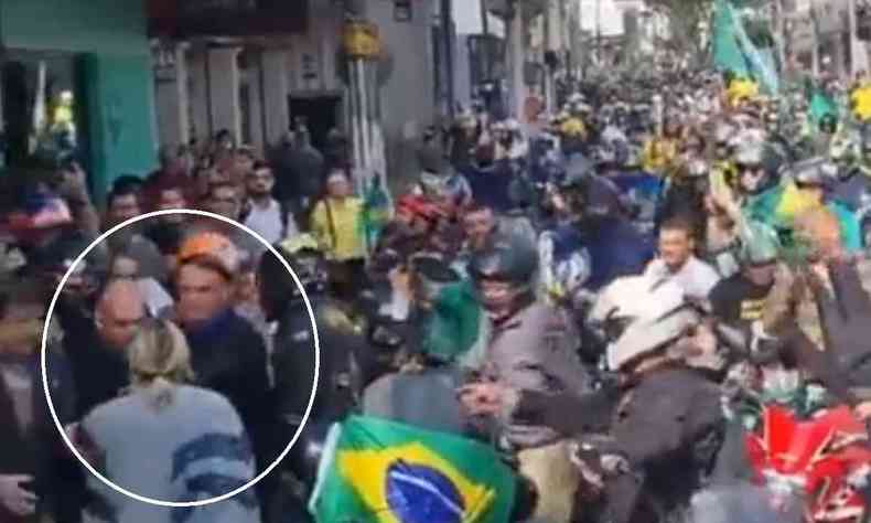 Frame de vdeo com Bolsonaro rodeado por apoiadores; no canto inferior esquerdo aparece o presidente com a mo esticada na direo da vtima