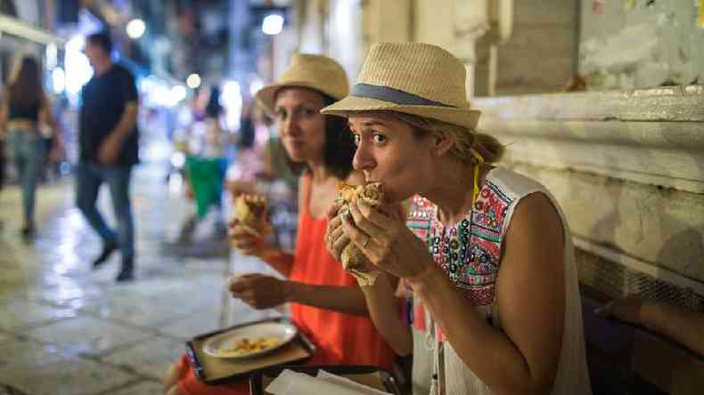 Duas turistas comendo sanduche na rua