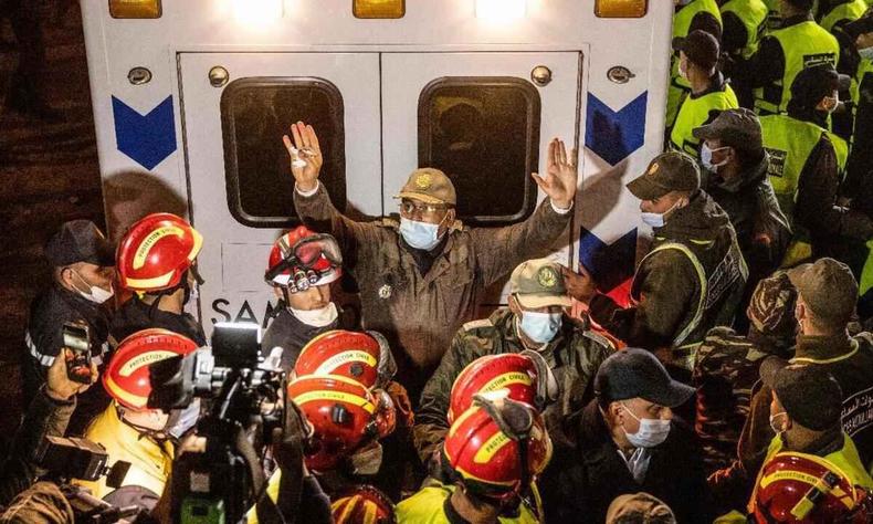 Integrante das foras de segurana marroquinas gesticula para que a multido se afaste, enquanto a ambulncia que transporta o corpo de Rayan deixa o local na remota vila de Ighrane