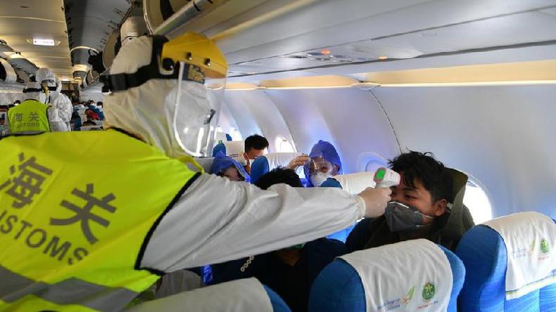 Funcionrio da imigrao realiza verificao de temperatura a bordo depois que um voo pousou na China