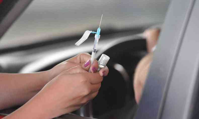 Enfermeira preparando seringa com vacina para aplicação