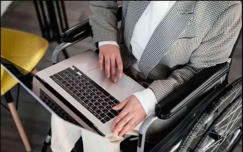 Pessoa com deficincia sentada em uma cadeira de rodas e com um notebook no colo
