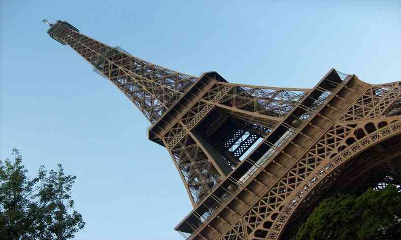 Torre Eiffel visto de baixo para cima, de cor amarronzada com cu limpo no fundo.