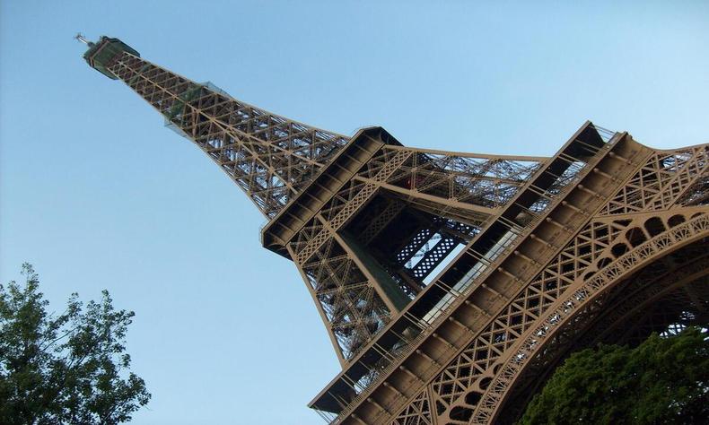 Torre Eiffel visto de baixo para cima, de cor amarronzada com cu limpo no fundo.