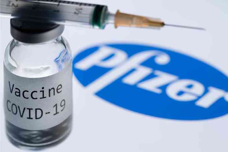 Uma seringa e um frasco com os dizeres 'vacina covid-19' em frente ao logo da farmacêutica Pfizer, em 23 de novembro de 2020 ( AFP / JOEL SAGET)