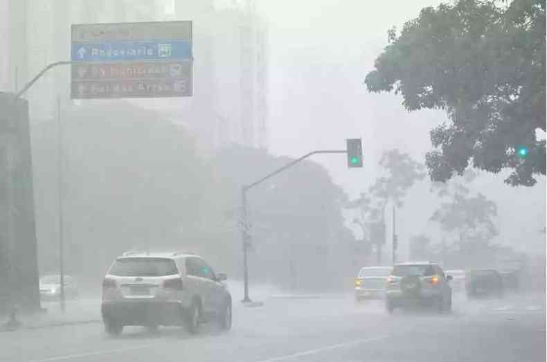 Avenida com muita chuva e carros passando