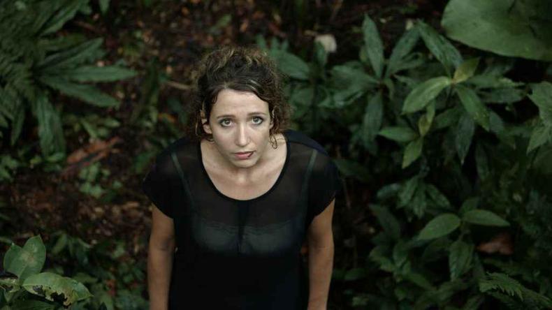 Rita Carelli, de p em paisagem com vegetao, usando camiseta escura, olha para a cmera, situada em plano areo