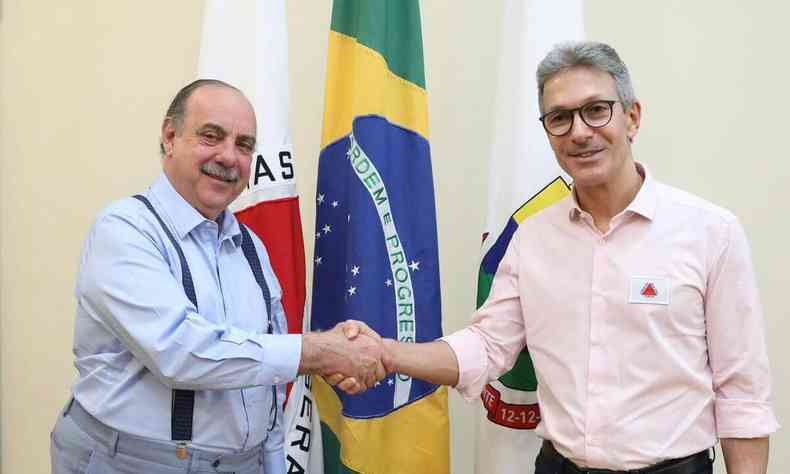 Prefeito Fuad Noman e Governador Romeu Zema apertam as mos; ao fundo as bandeiras de Minas Gerais, Brasil e de Belo Horizonte respectivamente