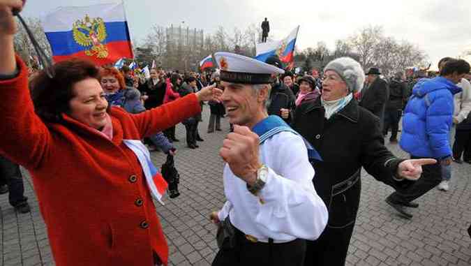 Com bandeiras da Unio Sovitica e da Rssia, ucranianos da Crimeia comemoraram a ida s urnas(foto: AFP PHOTO/ VIKTOR DRACHEV )