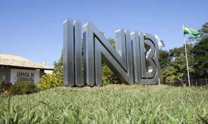 INB afasta gerente da unidade de Resende (RJ) por falas racistas e lgbtfóbicas(foto: INB/Divulgação) Foto externa da base da INB em Resende. Observa-se o logo da empresa (as letras INB) em metal prata acima de uma elevação de terra coberta de grama verde
