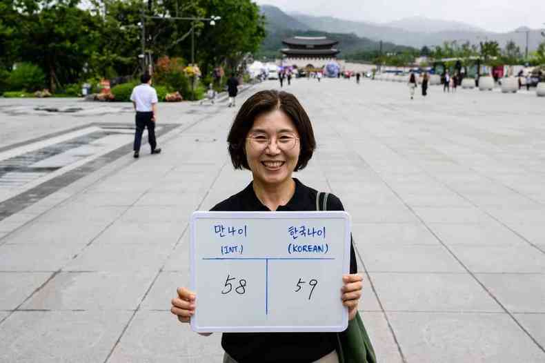 Mulher mostra cartaz com a idade internacional dela e a idade na Coreia do Sul
