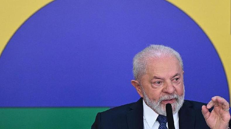 Lula gesticulando em frente a painel com cores do Brasil