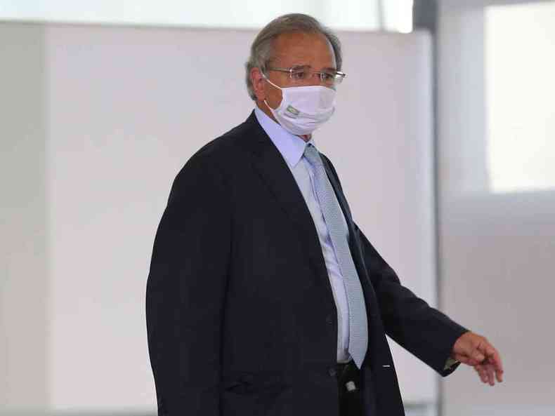 O ministro da Economia, Paulo Guedes usa máscara e caminha por um corredor