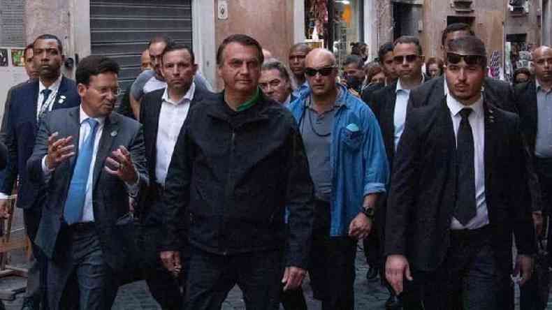 Bolsonaro caminha na rua rodeado de assessores e seguranas