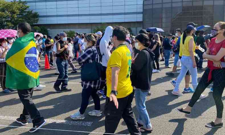 Fila em zona eleitoral no Japo. H um grande nmero de pessoas, muitas usando a camisa da seleo de futebol brasileira e a bandeira do Brasil. Alguns usam roupas casuais e poucos, roupas vermelhas