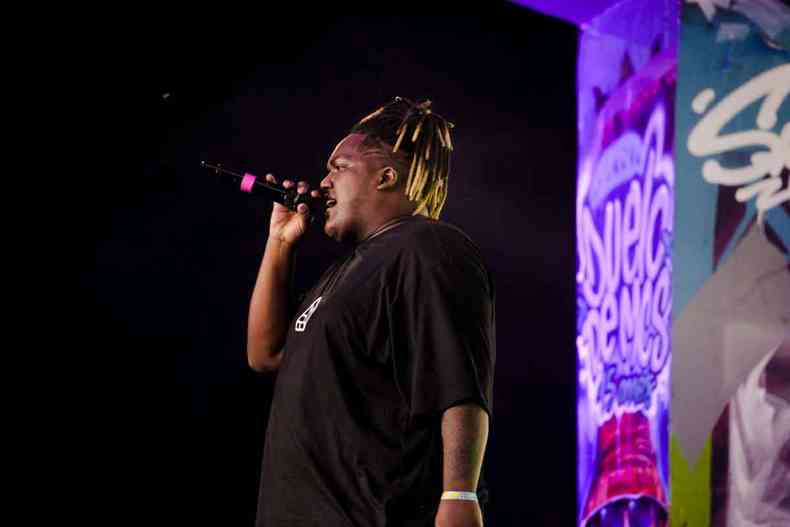 Rapper Big Mike est de lado, cantando no microfone, em evento realizado em BH