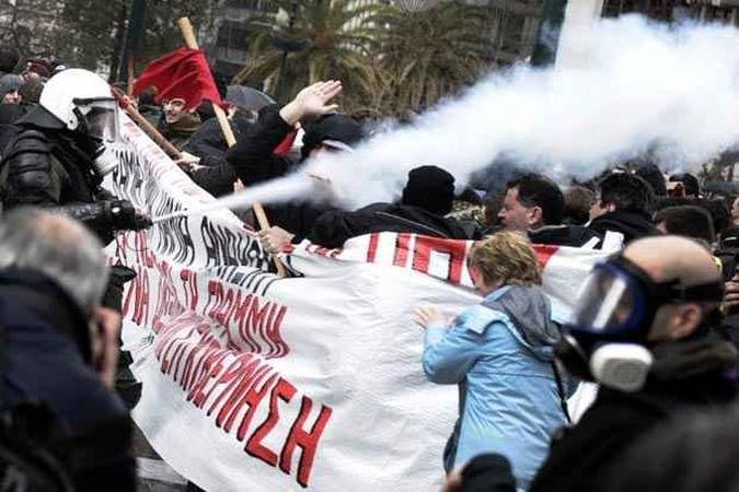 Policial joga spray de pimenta nos manifestantes da cidade de Atenas(foto: ARIS MESSINIS / AFP) Policial joga spray de pimenta nos manifestantes da cidade de Atenas(foto: ARIS MESSINIS / AFP)