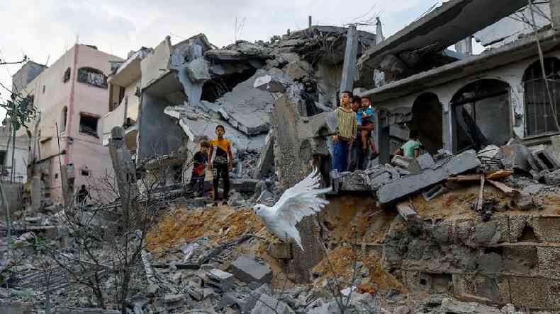 Uma pomba sobrevoa os escombros de casas em Khan Younis, no sul da Faixa de Gaza, em 11 de outubro de 2023