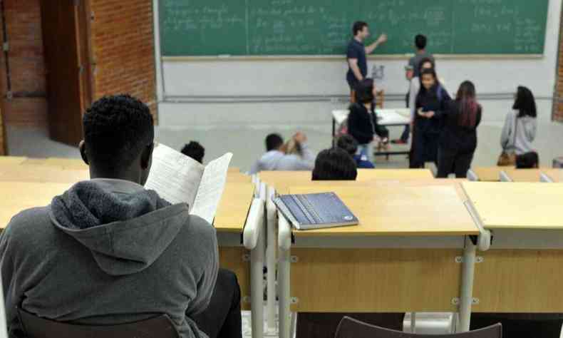Na foto, aluno estudando presencial na sala de aula da faculdade